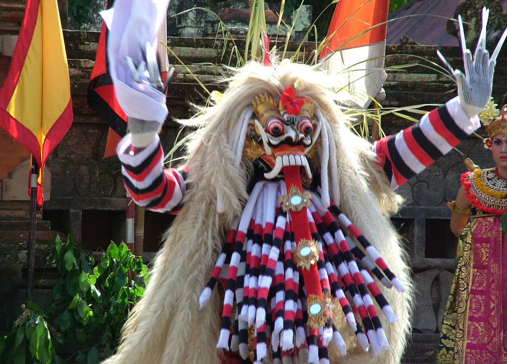  A dancer in a Balinese mythological creature costume is performing a traditional dance in a temple.