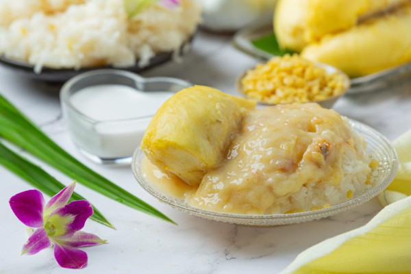 Ketan Durian yang Lezat: Sepiring ketan putih yang pulen disajikan dengan durian manis yang menggugah selera, siap untuk dinikmati
