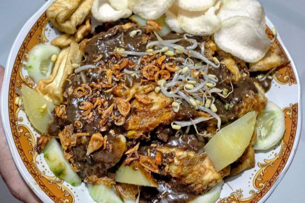 Tahu Tek khas Surabaya, lengkap dengan potongan tahu goreng, kentang, lontong, dan siraman bumbu kacang petis yang gurih